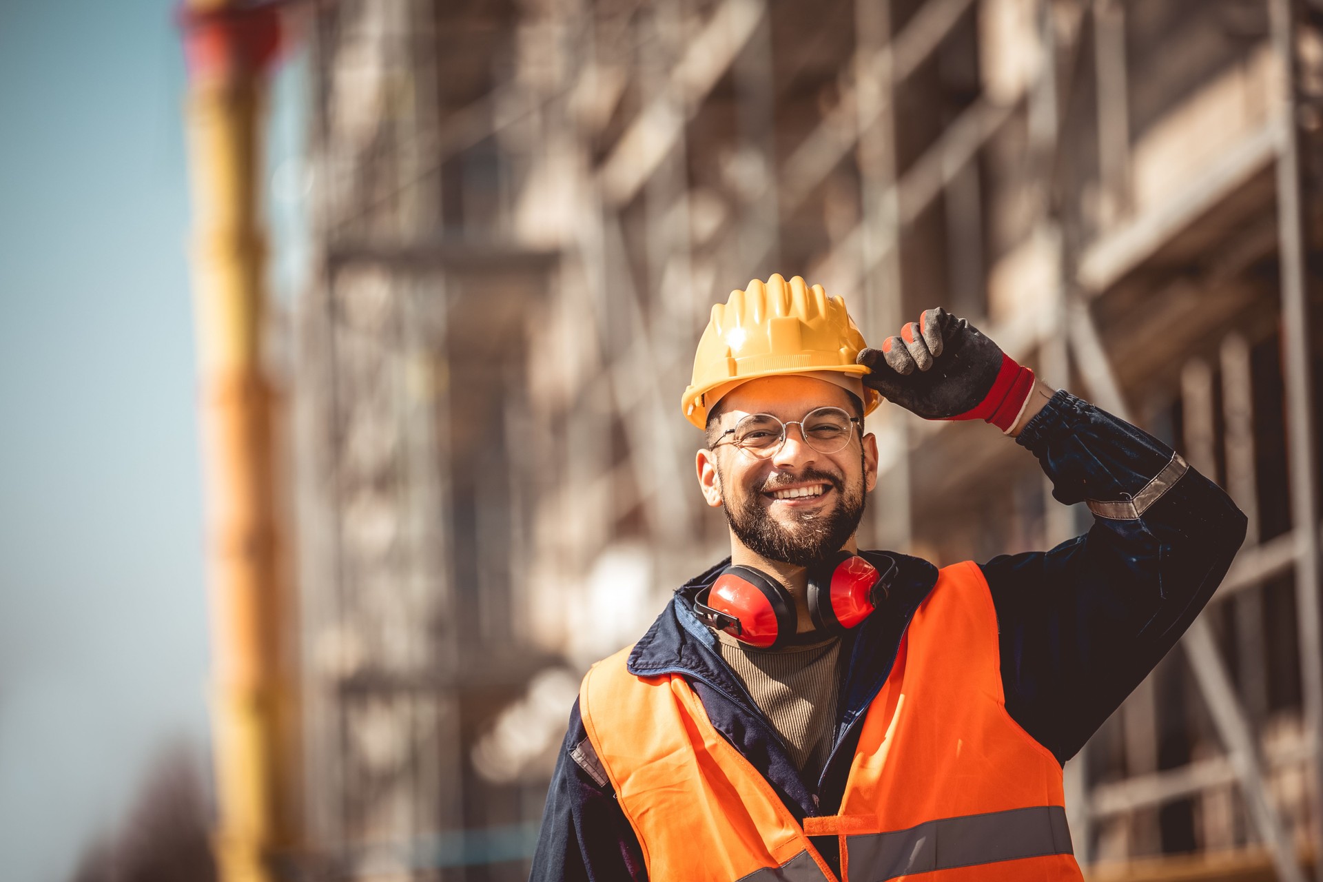Construction site manager standing  wearing safety vest and helmet, thinking at construction site.