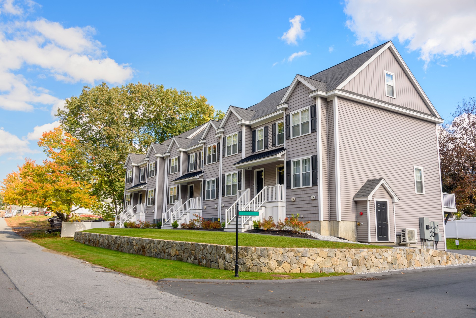 New Row houses with white stairs leading to the front doors on a sunny autumn day